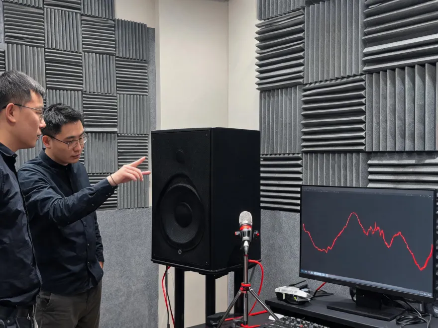 Audio engineers reviewing a professional loudspeaker in a measurement workspace